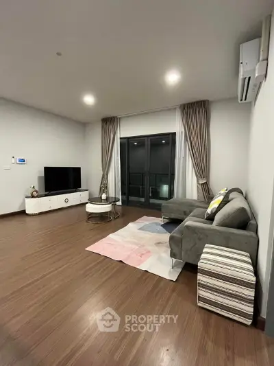Spacious modern living room with stylish decor and large windows.