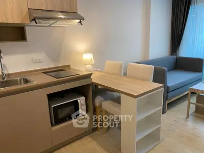 Modern compact living room with kitchenette, featuring cozy sofa and dining area in stylish apartment.
