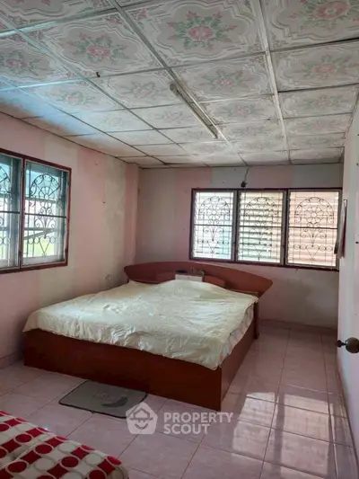 Cozy bedroom with vintage ceiling tiles and ample natural light.