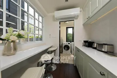 Modern kitchen with breakfast bar and view into laundry area