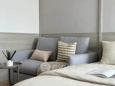 Cozy bedroom with stylish gray sofa and striped cushions, perfect for relaxation.