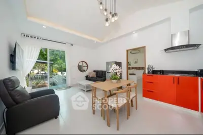 Modern open-plan living room with red kitchen cabinets and garden view