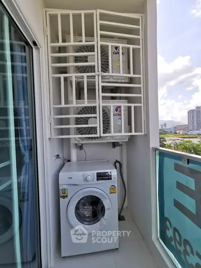 Compact balcony with washing machine and air conditioning units in modern apartment.