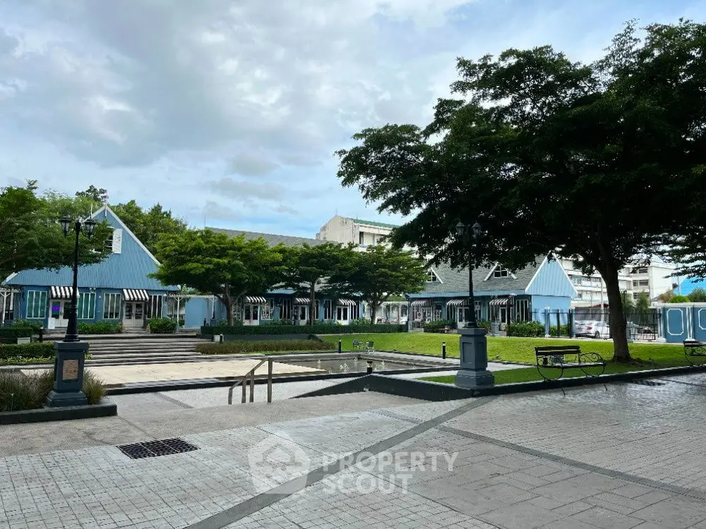 Charming blue building with lush greenery and spacious courtyard, perfect for commercial or residential use.