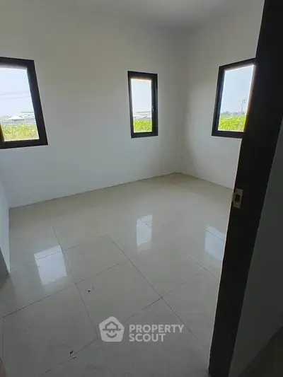 Bright empty room with large windows and tiled flooring, perfect for customization.