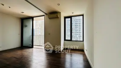 Spacious modern apartment with wooden flooring and balcony view in urban high-rise.