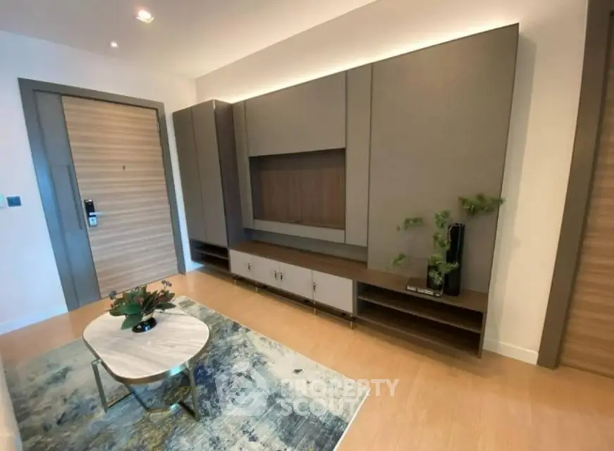 Spacious living room with modern built-in wall units and sleek wooden flooring, complemented by a stylish round coffee table and a contemporary rug.