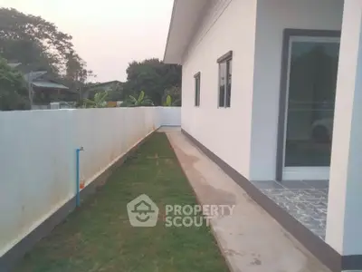 Modern exterior side view of a house with a narrow garden path and white walls.