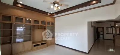 Spacious living room with built-in wooden cabinets and ceiling fan