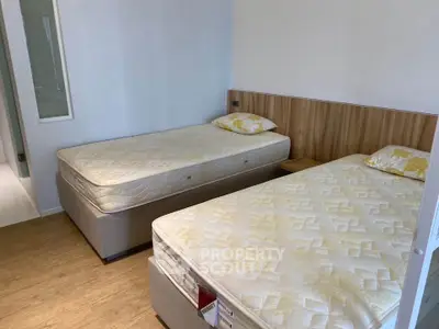 Modern bedroom with twin beds and wooden flooring, perfect for a cozy living space.