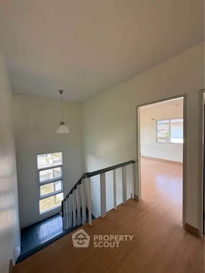Bright and airy stairway leading to a spacious room with wooden flooring and large windows.