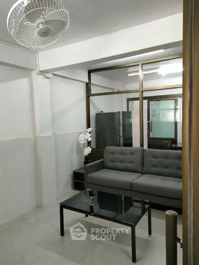 Cozy living room with modern gray sofa and glass coffee table, ideal for relaxation and entertaining.