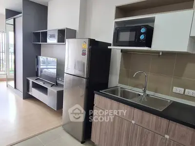 Modern kitchen with sleek cabinetry, stainless steel fridge, and built-in microwave in a stylish apartment.