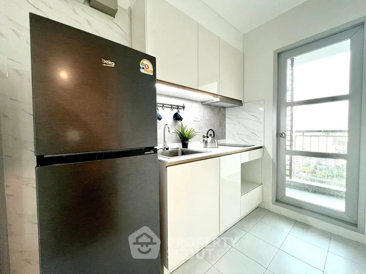 Modern kitchen with sleek appliances and balcony view, perfect for urban living.