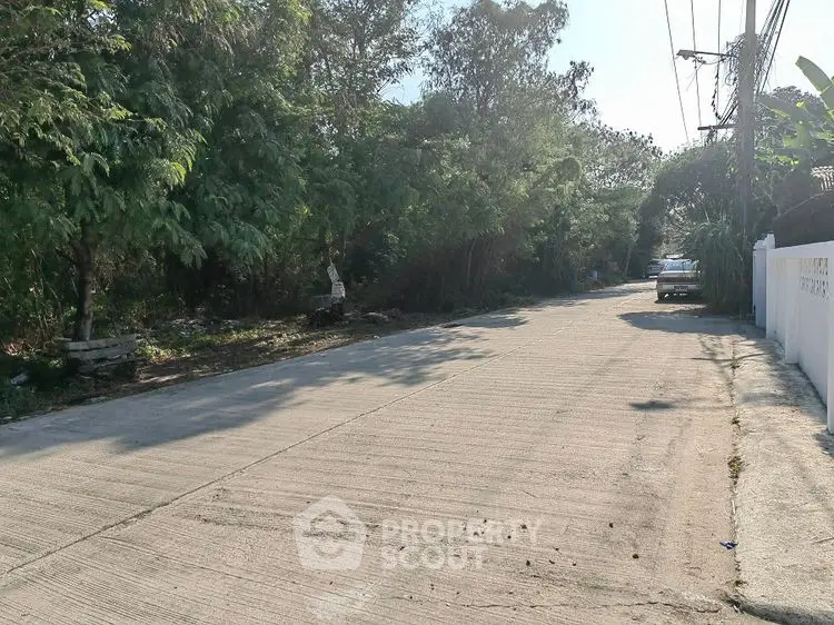 Quiet residential street with lush greenery and parked car, ideal for peaceful living.