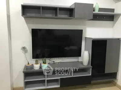 Modern living room with sleek gray entertainment unit featuring ample shelving and a large flat-screen TV, perfect for cozy family evenings.