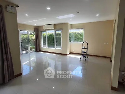 Spacious living room with large windows and garden view, perfect for family gatherings.