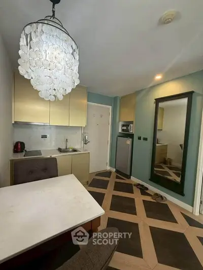 Chic modern kitchen with unique flooring and elegant chandelier in a compact apartment setting.