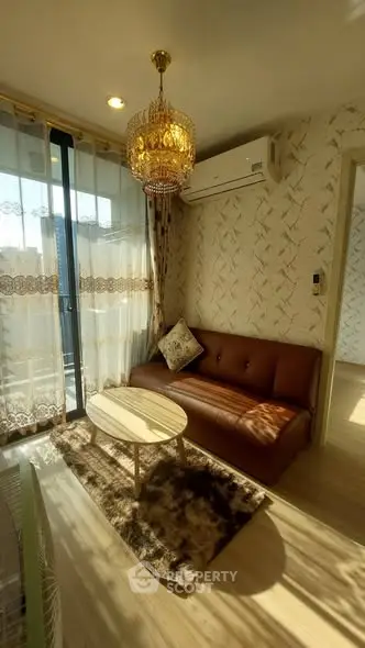 Charming living room with elegant chandelier and cozy sofa, featuring natural light and stylish decor.