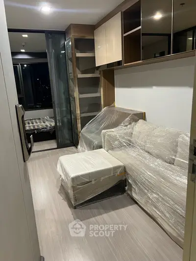Modern apartment interior with sleek furniture and stylish decor, featuring a cozy living area and a glimpse of the bedroom.