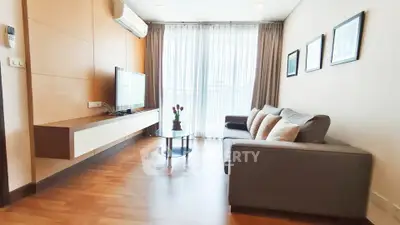 Modern living room with sleek furniture and large window offering natural light.
