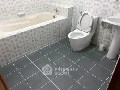Spacious bathroom with bathtub and modern fixtures in a stylish tiled setting.