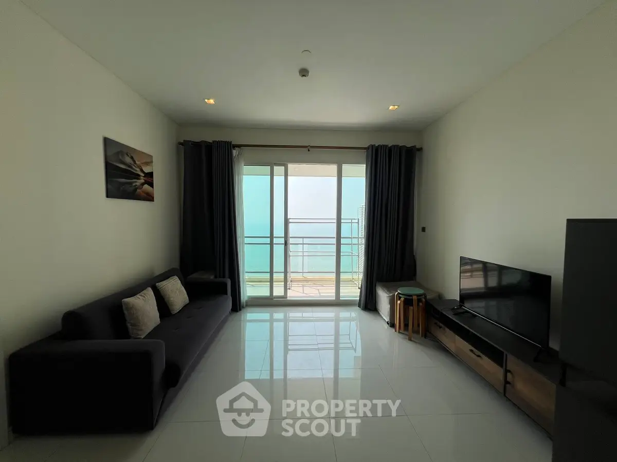 Modern living room with ocean view, sleek furniture, and large sliding glass doors leading to a balcony.
