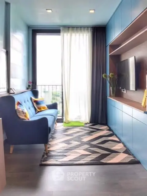 Stylish living room with modern blue sofa and large window offering natural light and city view.