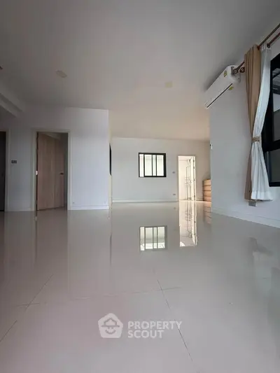 Spacious modern living room with glossy tiled floors and large windows for natural light.