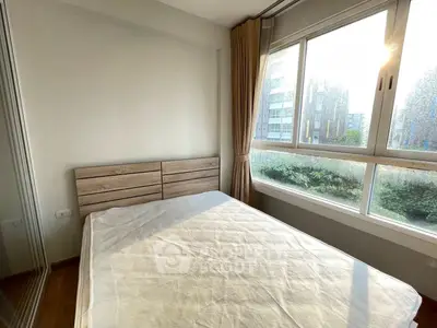 Bright bedroom with large window and wooden bed frame, offering serene garden views.