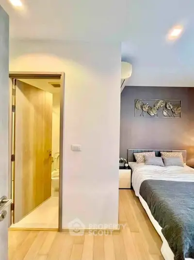 Modern bedroom with ensuite bathroom, featuring elegant decor and wooden flooring.