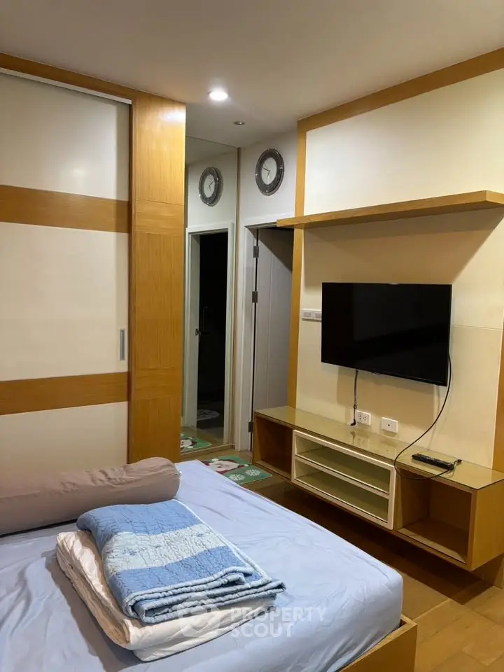 Cozy bedroom with modern TV setup and ample storage space