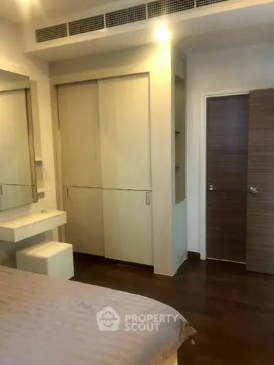 Modern bedroom with sleek wooden flooring and built-in wardrobe, perfect for stylish living.