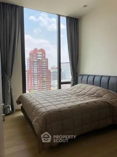Modern bedroom with large window offering stunning city view in high-rise apartment.