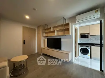 Modern living room with open kitchen, featuring sleek wooden cabinetry and built-in appliances.