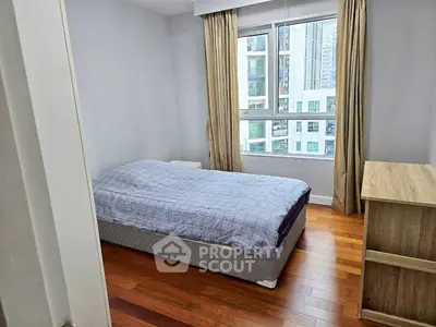 Cozy bedroom with city view and wooden flooring in modern apartment