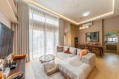 Spacious living room with high ceilings and modern decor, featuring a cozy sectional sofa and large windows.