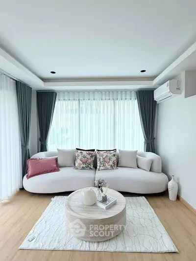 Modern living room with elegant white sofa, stylish decor, and large windows with natural light.