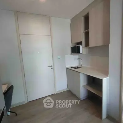 Modern compact kitchen with sleek cabinetry and integrated appliances in a cozy apartment.
