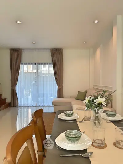 Elegant living room with cozy seating and dining area, featuring stylish decor and natural light.