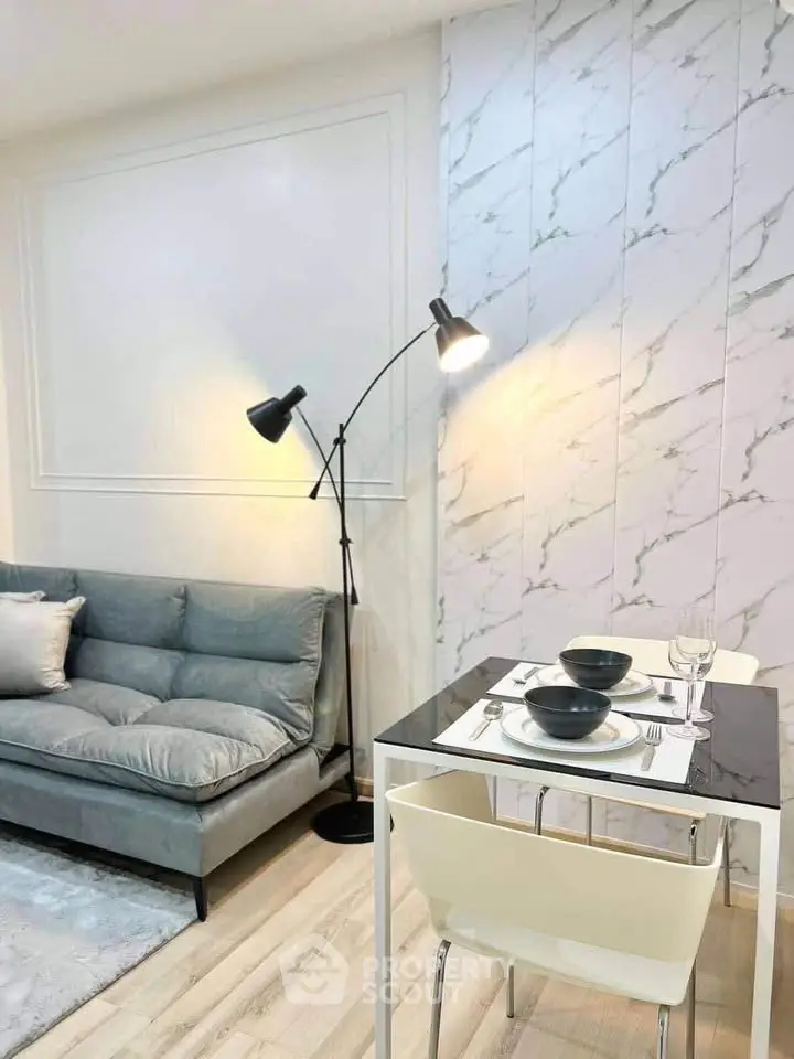 Modern living room with stylish decor and dining area, featuring a cozy sofa and elegant lighting.