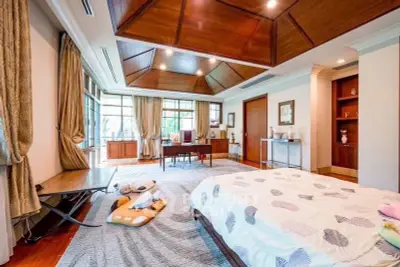 Luxurious bedroom with elegant wooden ceiling and large windows offering natural light.