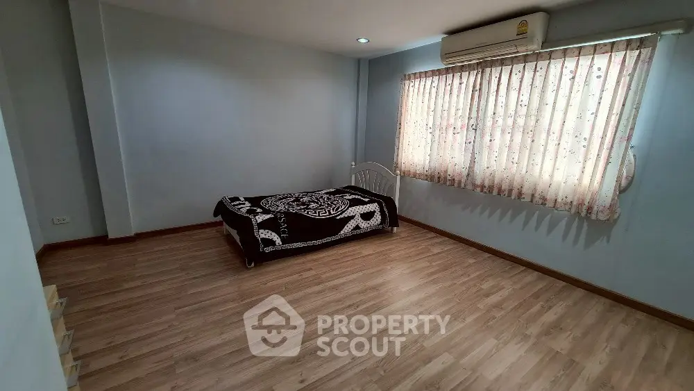 Spacious bedroom with wooden flooring and natural light