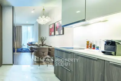 Modern open-layout kitchen and living room with stylish decor and natural light.
