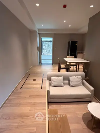 Modern living room with sleek furniture and open layout, featuring a cozy sofa and dining area.