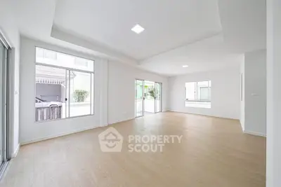 Spacious and bright living room with large windows and wooden flooring in modern home.