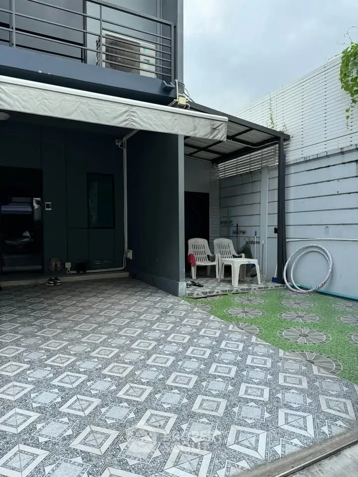 Modern home exterior with tiled patio and seating area, perfect for outdoor relaxation.