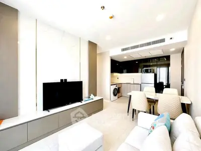 Modern open-plan living room with sleek kitchen and dining area, featuring stylish furniture and appliances.