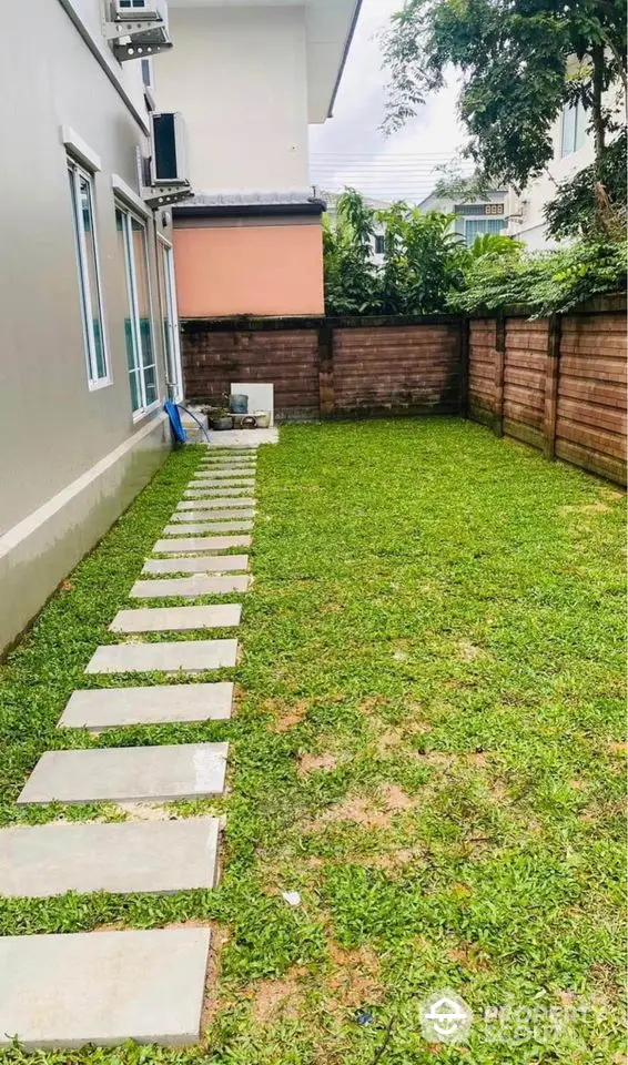 Charming backyard with lush green lawn and stepping stones, perfect for outdoor relaxation and entertainment.