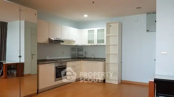 Modern kitchen with sleek cabinetry and built-in oven in a spacious apartment.